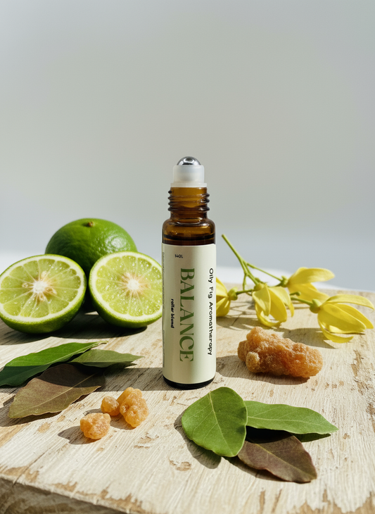 Bottle labeled 'Balance' roller blend with limes, leaves, and flowers on a wooden surface